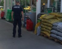Policjant stoi przy gaśnicy na stacji benzynowej
