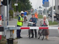 Policjant rozmawia z rowerzystami na przejeździe kolejowym