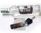 Na zdjęciu kluczyki do samochodu, butelka i dowód rejestracyjny pojazdu.