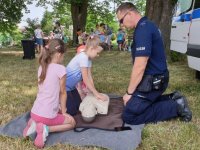 Na zdjęciu policjant uczy dzieci pierwszej pomocy.