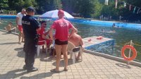 Na zdjęciu policjant kontroluje basen w Kokotku i rozmawia z ratownikiem..