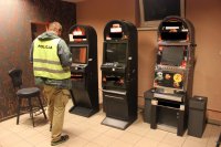 Na zdjęciu zarekwirowane automaty do gier hazardowych i policjant  operacyjny.