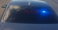 Na zdjęciu napis policja wyświetlany za tylna szybą policyjnego radiowozu nieoznakowanego