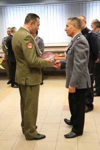 Na zdjęciu  uczestnicy pożegnania zastępcy komendanta powiatowego w Lublińcu. Odchodzący zastępca komendanta przyjmuje gratulacje.