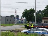 Na zdjęciu umundurowany policjant w czasie akcji &quot;Bezpieczny przejazd&quot; nadzorujący ruch pojazdów na przejeździe kolejowym.
